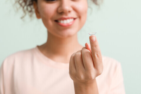 Woman holding contact lens on tip of her finger
