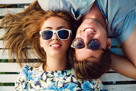 Couple wearing sunglasses lying on deck